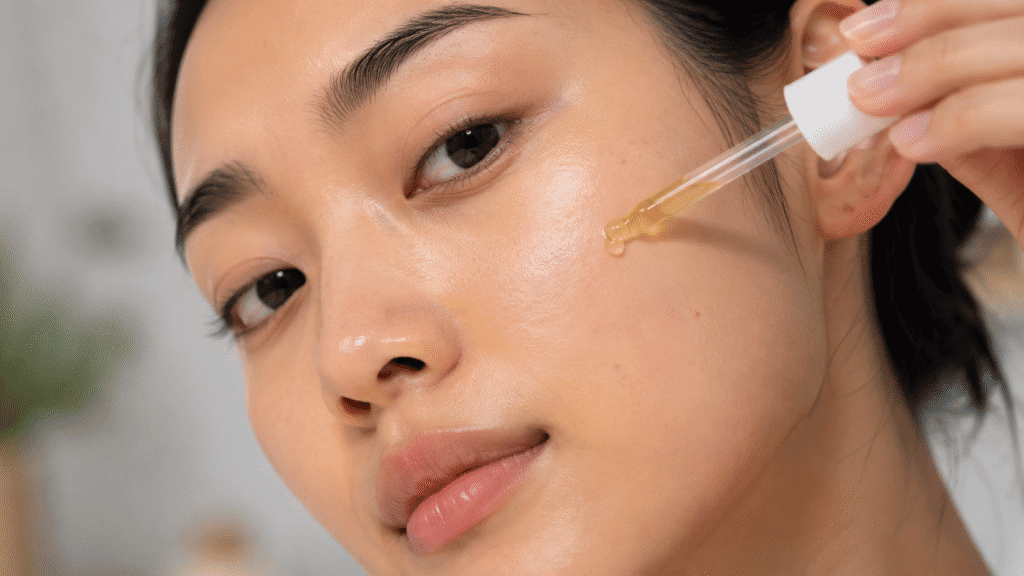 Jojoba Oil for Oily Skin: Does It Help? 5 Girl applying a drop of jojoba oil to her cheek.